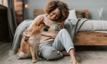 Een hondenoppas zit op de grond met een Shiba Inu